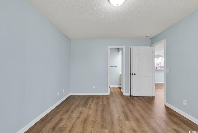 unfurnished room with baseboards, a textured ceiling, and wood finished floors