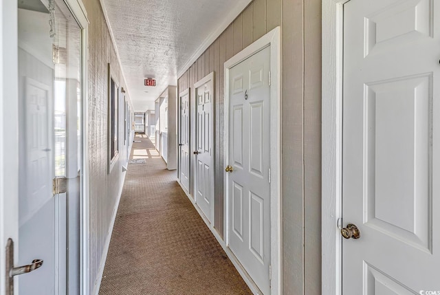 corridor with dark colored carpet and a textured ceiling