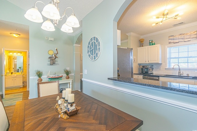 dining room featuring an inviting chandelier, visible vents, arched walkways, crown molding, and a textured ceiling
