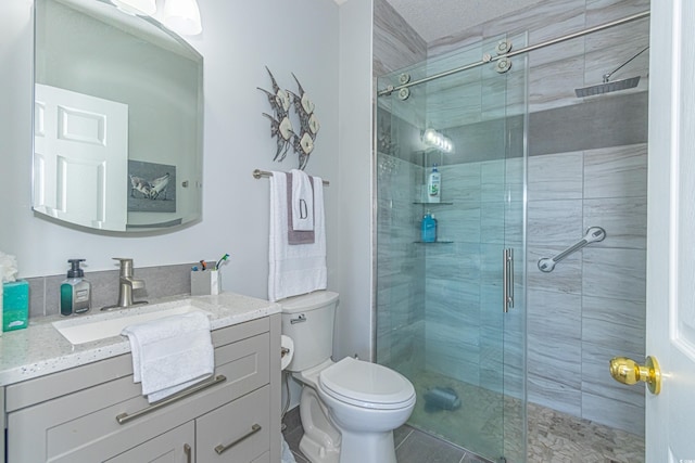 bathroom featuring a shower stall, toilet, vanity, and tile patterned floors