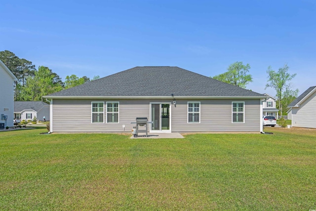 rear view of property featuring a yard, a patio area, and a shingled roof