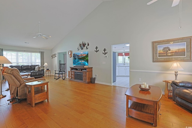 living area with high vaulted ceiling, a ceiling fan, visible vents, and light wood-style flooring
