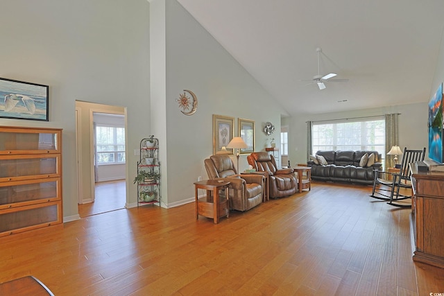 living area featuring light wood-style flooring, a wealth of natural light, high vaulted ceiling, and ceiling fan