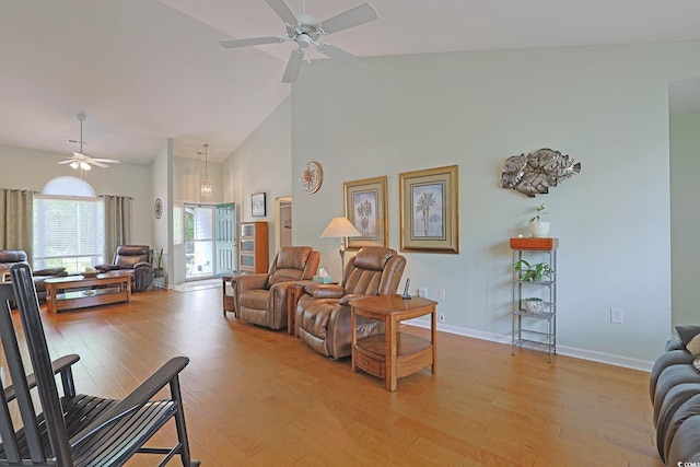living room with high vaulted ceiling, ceiling fan, baseboards, and light wood-style flooring