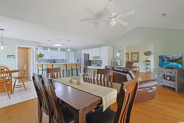 dining space featuring light wood-type flooring, visible vents, lofted ceiling, and ceiling fan