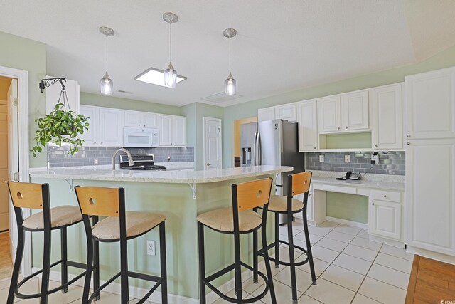 kitchen featuring white cabinetry, backsplash, appliances with stainless steel finishes, open shelves, and a breakfast bar area