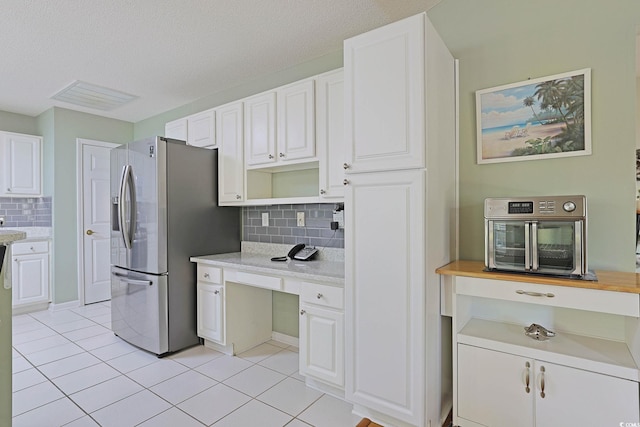 kitchen with visible vents, light tile patterned floors, decorative backsplash, stainless steel refrigerator with ice dispenser, and white cabinetry