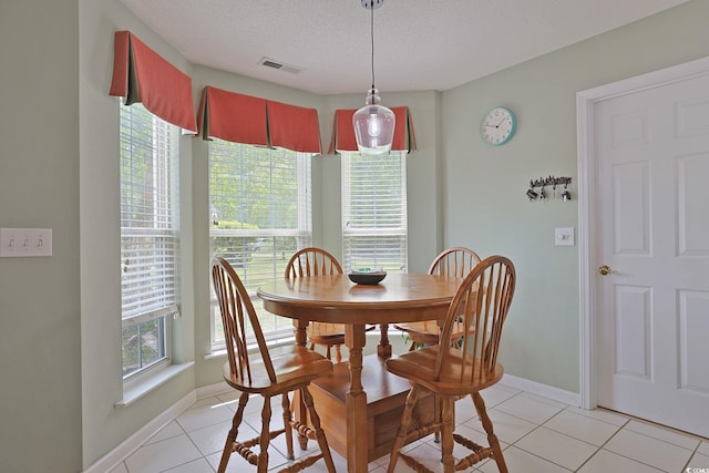 dining area featuring a textured ceiling, visible vents, baseboards, and light tile patterned floors