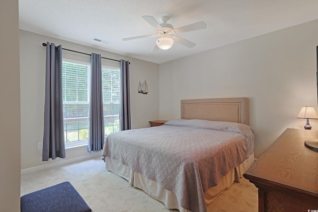bedroom featuring light carpet, visible vents, ceiling fan, and multiple windows