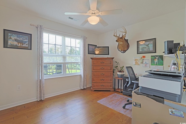 office space with light wood-type flooring, baseboards, a ceiling fan, and visible vents