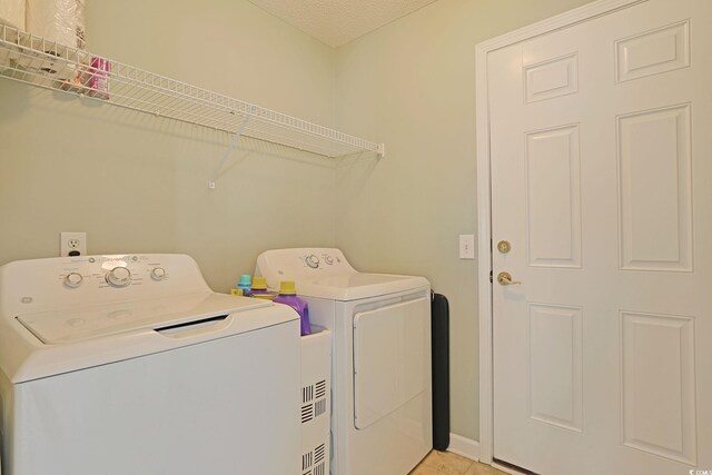 laundry room with baseboards, light tile patterned flooring, washer and clothes dryer, and laundry area
