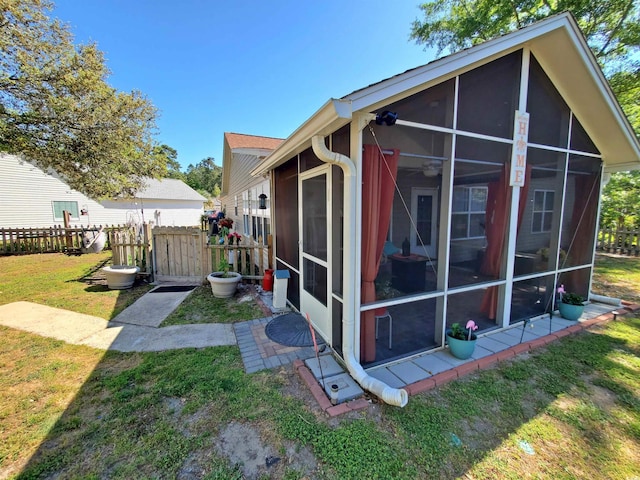 view of home's exterior with a sunroom, fence, and a lawn