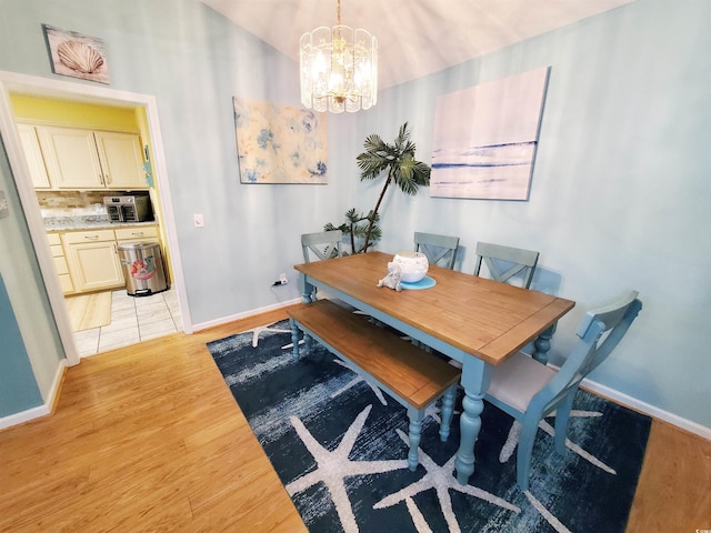 dining room featuring baseboards, a chandelier, and light wood-style floors