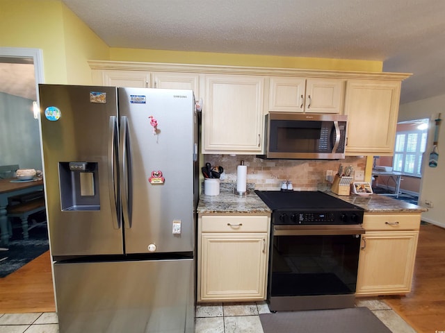 kitchen with decorative backsplash, appliances with stainless steel finishes, light stone countertops, and light wood finished floors
