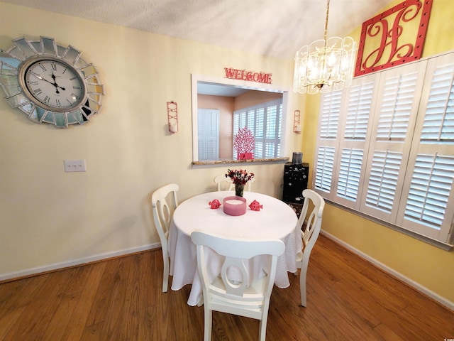 dining space with wood finished floors, baseboards, and an inviting chandelier