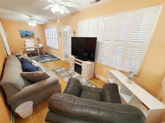 living area with wood finished floors, visible vents, baseboards, and ceiling fan