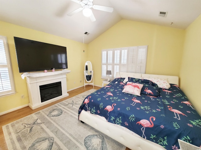 bedroom with vaulted ceiling, wood finished floors, visible vents, and a ceiling fan
