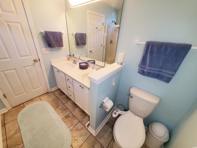 bathroom with toilet, a shower with door, a sink, and double vanity