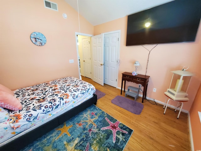 bedroom with baseboards, vaulted ceiling, visible vents, and light wood-type flooring