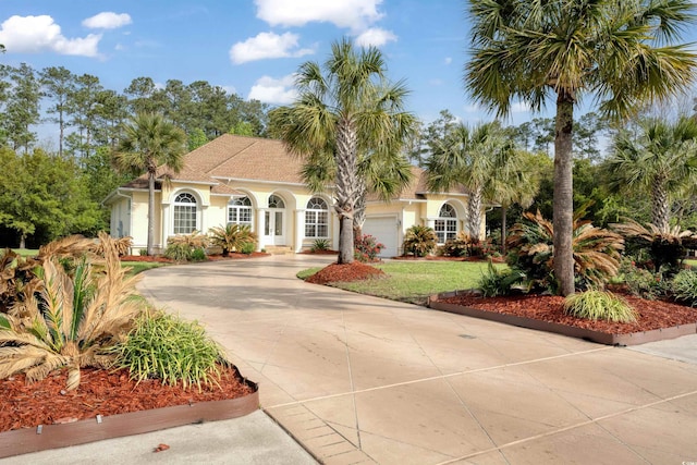mediterranean / spanish-style home featuring concrete driveway, a front lawn, a garage, and stucco siding