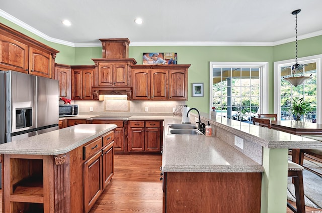 kitchen with a breakfast bar area, stainless steel appliances, open shelves, a sink, and a center island with sink