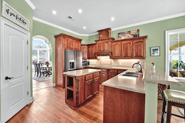 kitchen with a kitchen breakfast bar, a sink, appliances with stainless steel finishes, visible vents, and a peninsula