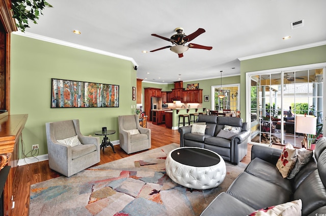 living room with visible vents, recessed lighting, ornamental molding, wood finished floors, and a ceiling fan