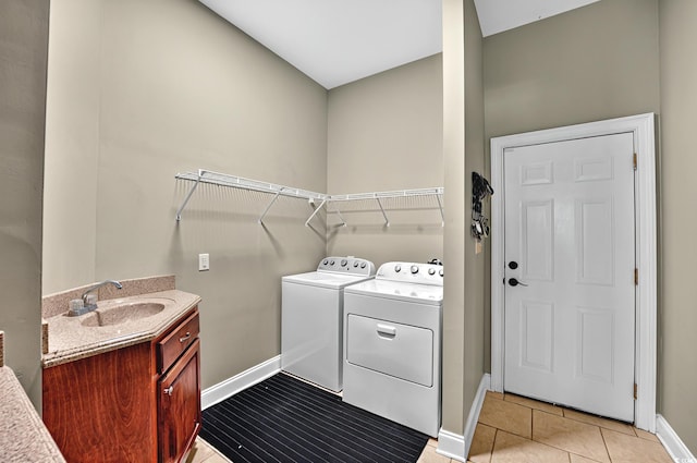 clothes washing area with laundry area, light tile patterned floors, washing machine and dryer, baseboards, and a sink