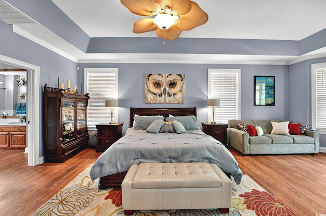 bedroom with visible vents, light wood-type flooring, multiple windows, and a tray ceiling