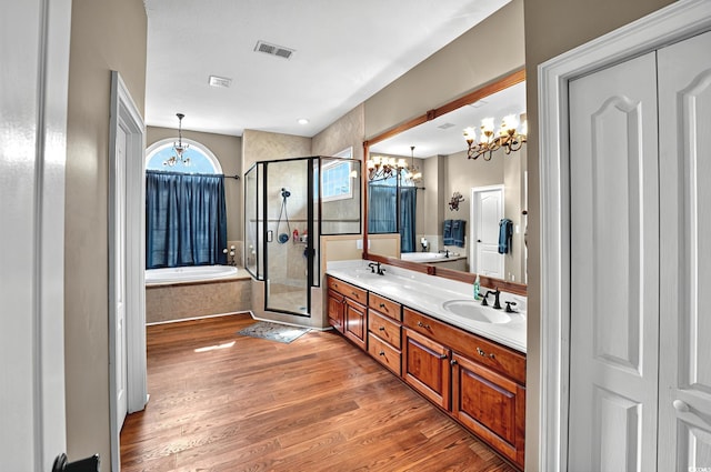 full bath featuring a chandelier, wood finished floors, a shower stall, and a sink