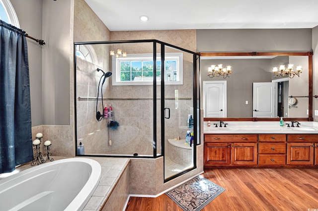 bathroom featuring a stall shower, a garden tub, wood finished floors, and a sink