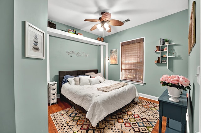 bedroom with baseboards, visible vents, wood finished floors, and a ceiling fan
