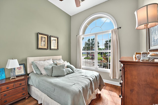 bedroom with a ceiling fan, baseboards, and dark wood-type flooring