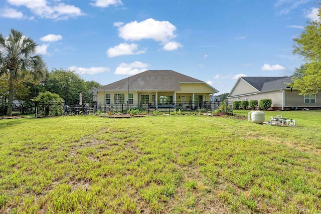 rear view of property with fence and a lawn