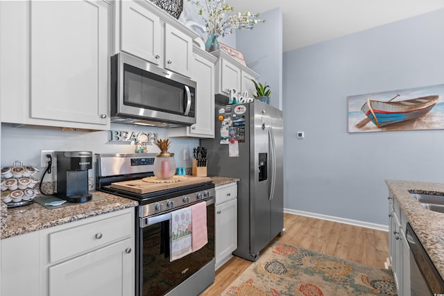 328 Logan St, Little River, SC 29566 - kitchen with light wood-style flooring, light stone counters, baseboards, white cabinets, and appliances with stainless steel finishes