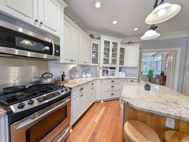 710 Masters Dr, Pawleys Island, SC 29585 - kitchen with crown molding, white cabinetry, stainless steel appliances, and light wood finished floors