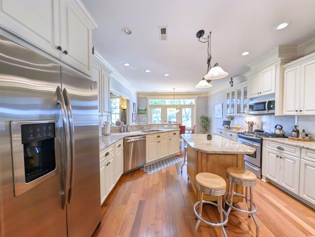 710 Masters Dr, Pawleys Island, SC 29585 - kitchen featuring light wood-type flooring, stainless steel appliances, a center island, and crown molding