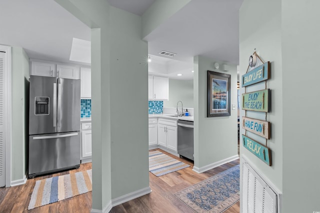 kitchen with visible vents, white cabinets, stainless steel appliances, and light wood-style floors