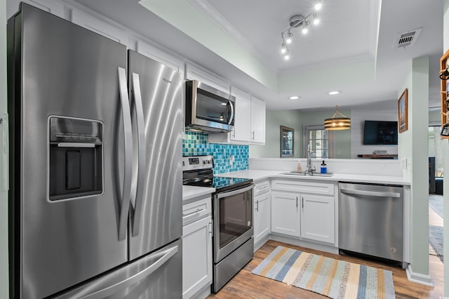 kitchen featuring stainless steel appliances, light countertops, white cabinetry, visible vents, and a tray ceiling