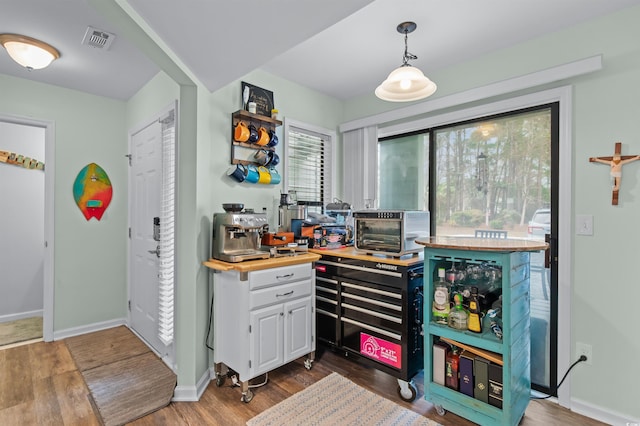 interior space featuring visible vents, white cabinetry, baseboards, a toaster, and wood finished floors