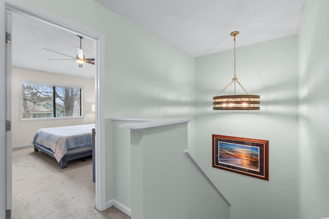 hallway featuring an upstairs landing, carpet, and baseboards