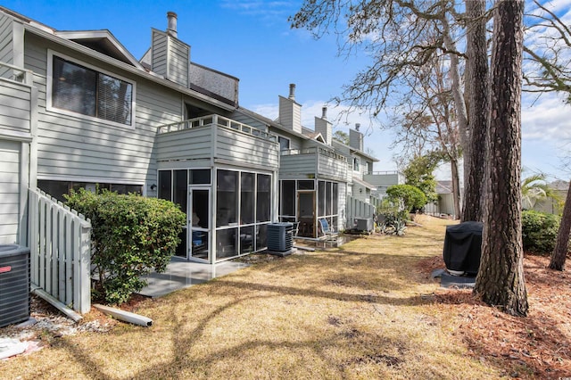 rear view of house with a chimney, central AC unit, a balcony, and a sunroom