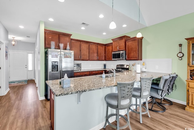 kitchen featuring a peninsula, wood finished floors, appliances with stainless steel finishes, and a sink