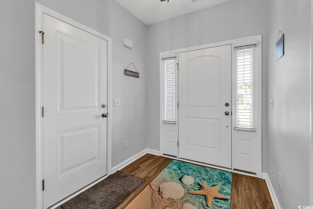 foyer featuring baseboards and dark wood-type flooring