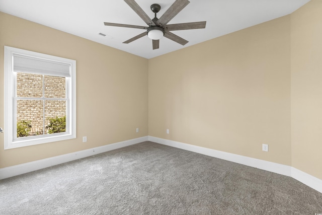 carpeted spare room with baseboards, a ceiling fan, and visible vents