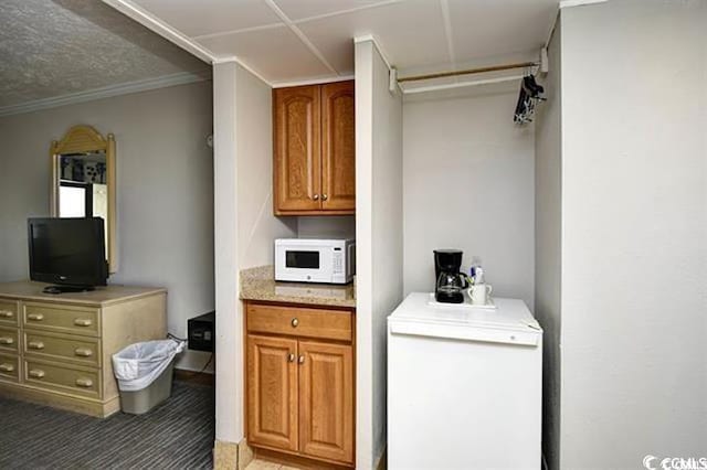 7100 N Ocean Blvd Unit 405, Myrtle Beach, SC 29572 - kitchen featuring white microwave, light countertops, brown cabinets, ornamental molding, and refrigerator