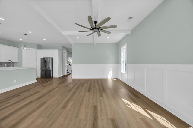 868 Crystal Water Way, Myrtle Beach, SC 29579 - unfurnished living room with wood finished floors, beam ceiling, a wainscoted wall, ceiling fan, and recessed lighting