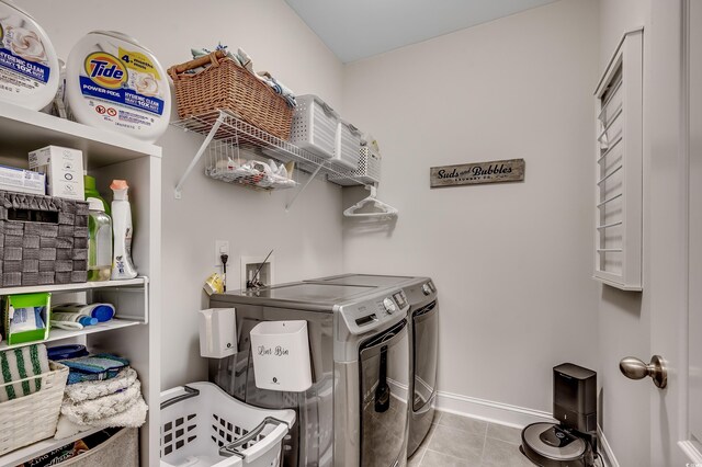 laundry area featuring washer and clothes dryer, tile patterned flooring, and baseboards