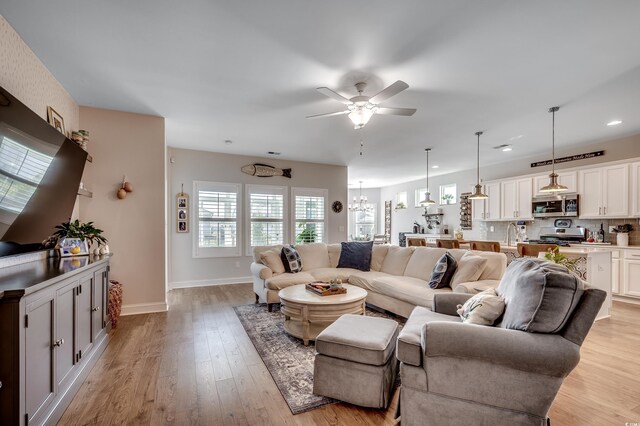 living area with light wood-style floors, a ceiling fan, baseboards, and recessed lighting