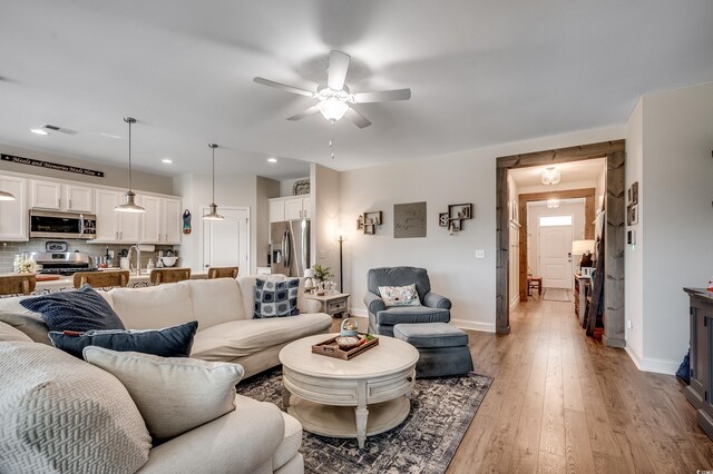 living room with baseboards, ceiling fan, light wood-type flooring, and recessed lighting